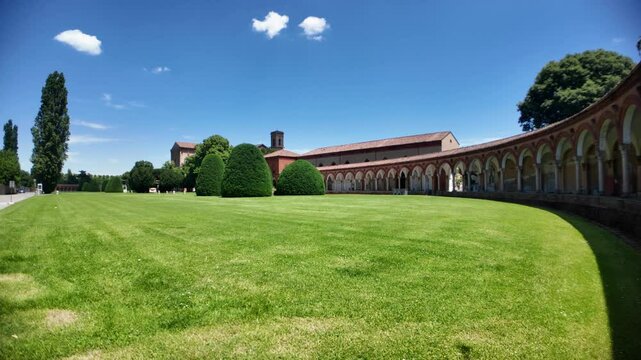 Ferrara, Italy - May 17, 2025: Monumental cemetery of the Charterhouse of Ferrara in Italy features a curved portico with arches and columns surrounding a green lawn under a clear blue summer sky
