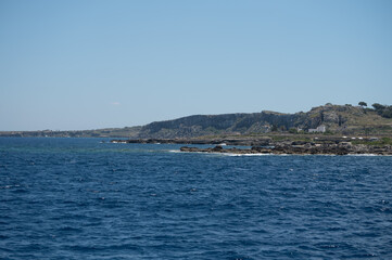 Naklejka premium Boat trip and view on coastline of Favignana island with shallow bays with clear turquoise water, tuff rocks, abandoned quarries, caves, Egadi Islands near Sicily, Italy