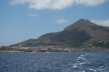 Boat trip and view on coastline of Favignana island with small village, shallow bays with clear turquoise water, tuff rocks, abandoned quarries, caves, Egadi Islands near Sicily, Italy