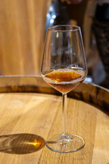 Visit of wine cellar with old large oak barrels, glass of fortified dry or sweet tasty marsala wine from barrels in Marsala, Sicily, Italy