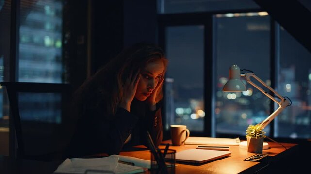 Weary worker touching forehead remaining long hours inside workspace closeup