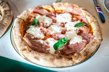 A Parma Ham and Stracciatella pizza is served in an Italian restaurant.