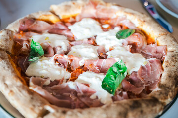 A Parma Ham and Stracciatella pizza is served in an Italian restaurant.