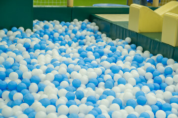 Obraz premium A vibrant indoor play space features a large ball pit filled with blue and white balls.