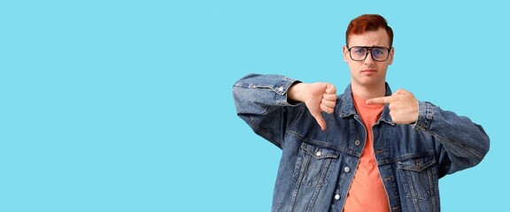 Young man showing dislike on blue background with space for text