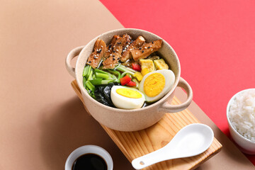Cooking pot with tasty Chinese soup and soy sauce on color background