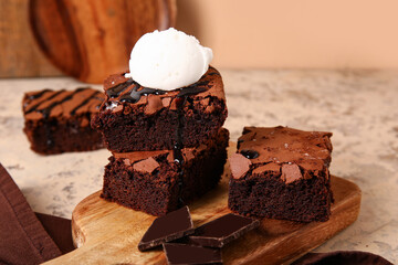 Wooden board with pieces of tasty chocolate brownie and ice cream on table