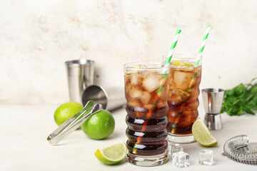 Glasses of cold Cuba Libre cocktail on light background