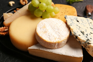 Different types of tasty cheese on dark background
