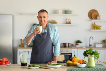 Mature man with glass of fresh vegetable smoothie in kitchen
