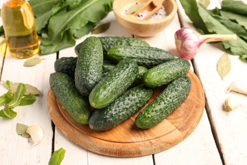 Board with fresh cucumbers for preservation on light wooden background