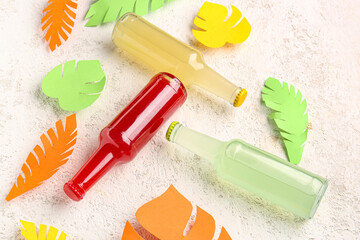Composition with bottles of fresh soda and paper leaves on light background