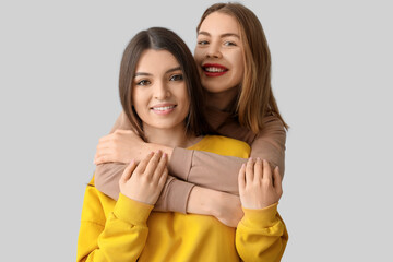 Female friends hugging on light background, closeup