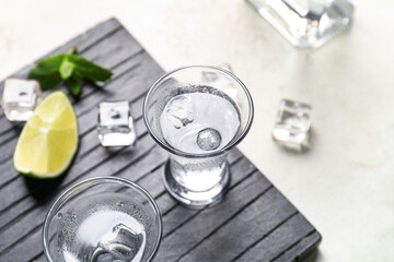 Glasses of cold vodka on light background