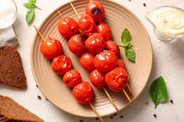 Plate of skewers with tasty grilled tomatoes and basil on white background