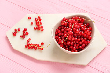 Bowl with fresh red currant on pink wooden background, closeup