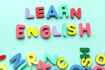 Text LEARN ENGLISH and wooden letters on turquoise background