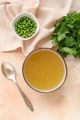 Bowl of tasty vegetable broth on beige background