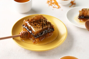 Plate with sweet honeycomb on light background