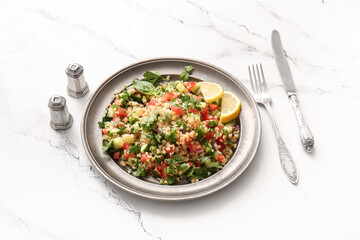 Plate with delicious tabbouleh salad and cutlery on light background