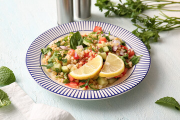 Plate with delicious tabbouleh salad on light background, closeup