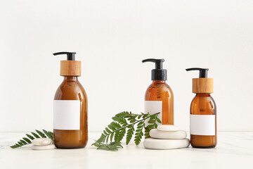 Bottles of shampoo and spa stones on white background