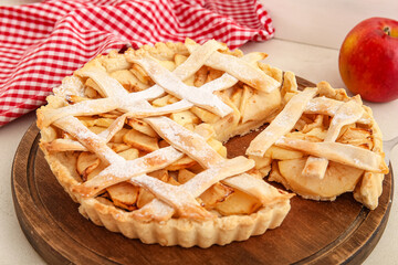 Wooden board with delicious apple pie on white background