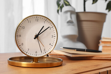 Wooden cabinet with alarm clock, books and houseplant, closeup