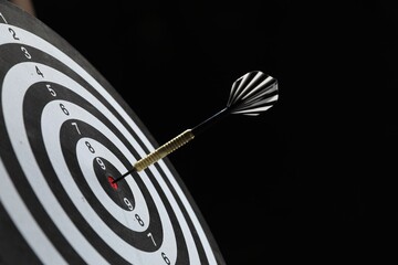 Targeting. Dart board with arrow on black background, closeup