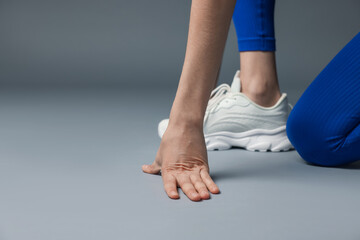 Runner in starting position on gray background, closeup. Space for text