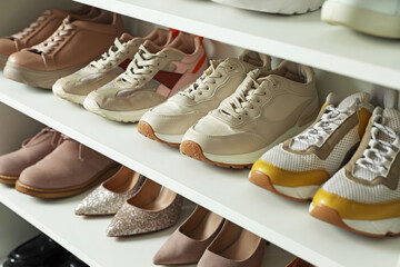 Different footwear on shelves indoors, closeup. Shoe storage