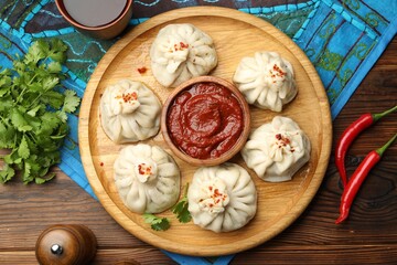 Delicious khinkali served with sauce on wooden table, flat lay