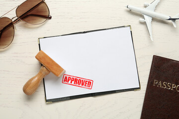Red stamp Approved in passport. Flat lay composition with toy plane, passports and wooden stamp on...
