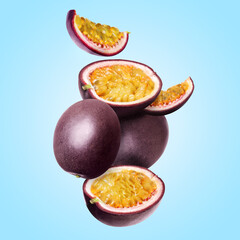 Delicious ripe passion fruits falling on light blue background