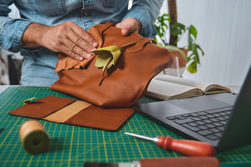 Leather craftsman polishing a bag in his workshop, using a piece of cloth