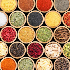 Set of different aromatic spices in bowls on black background, flat lay