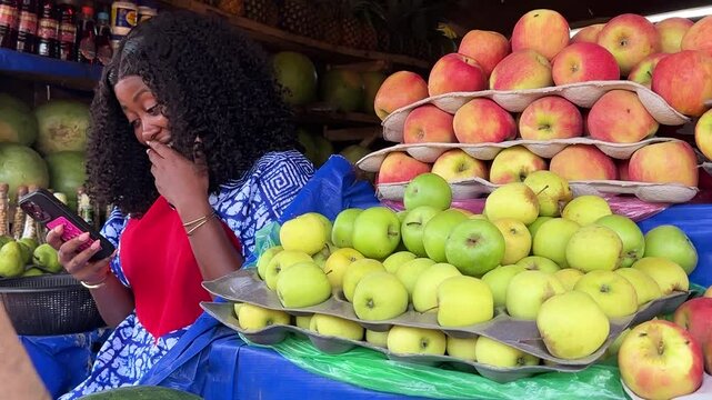 copy space of excited black female fruit salesperson using modern phone