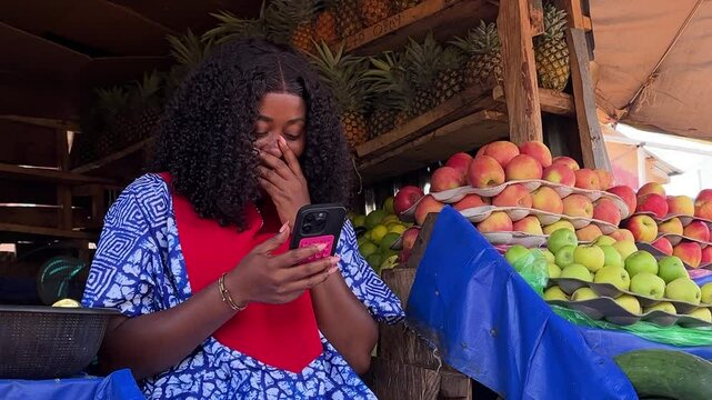 happy fruit salesperson using mobile at fruit market stand