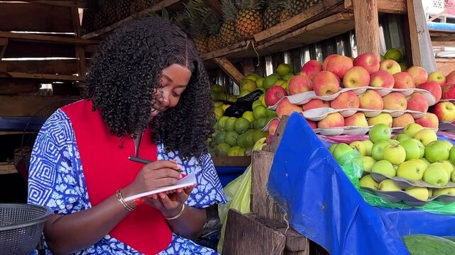 close up video of black young female shop keeper smiling book recording business sales