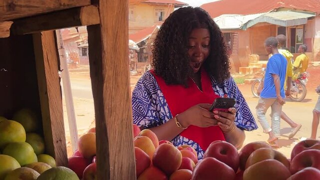 woman holding and using mobile phone at fruit market stand