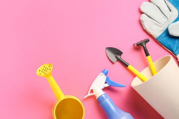 Gardening tools, glove, sprayer and watering can on pink background