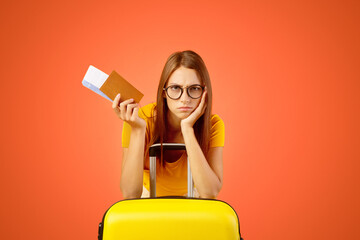 Upset young woman with passport and plane tickets leaning on suitcase, missed her vacation because...