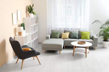 Stylish living room with comfortable sofa, coffee table, black armchair and curtains