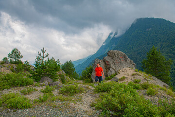 A man in red stands in the mountains of Georgia
