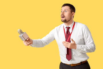 Male reporter with microphone on yellow background