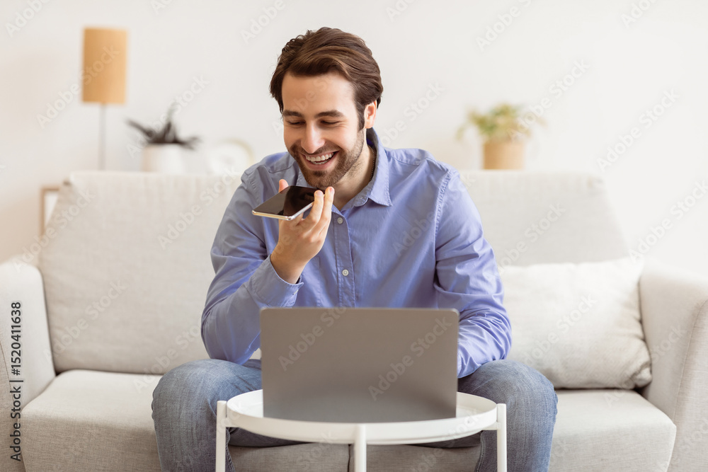 Poster smiling businessman talking by phone in loudspeaker mode or using voice assistant on smartphone sitt