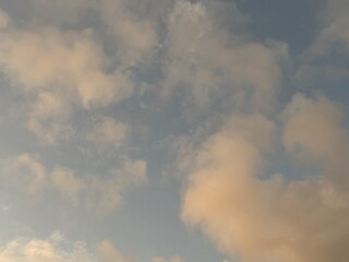 calm sky photo with soft and thin clouds golden light of the sun, light and shadow on the clouds create texture, bright blue sky calming background. Suitable for nature, tranquility, weather, freedom