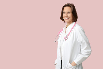 Beautiful female doctor with stethoscope on pink background