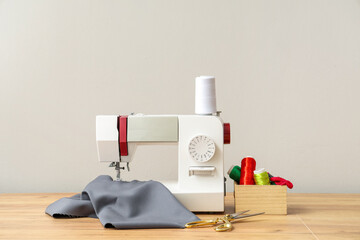 Modern sewing machine with tailor's supplies on wooden table