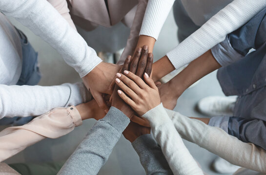 Close up of international business team showing unity with putting their hands together on top of each other. Concept of teamwork, top view